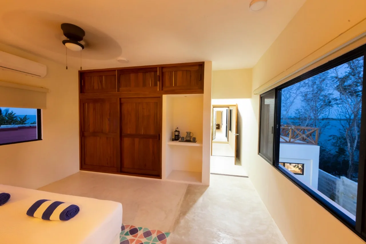 The Garden Room at dusk, with wooden wardrobes and a wide window toward the lagoon